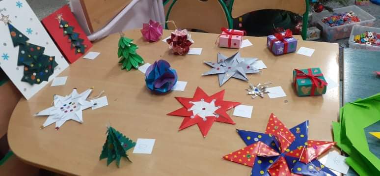Na zdjęciu widać ozdoby świąteczne z papieru ( gwiazdki, choinki, bombki) wykonane techniką origami.
