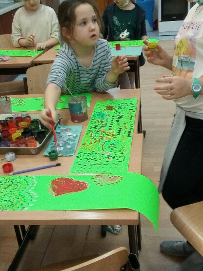 Na zielonych kartkach dziewczynki malują prace metodą kropkowania.