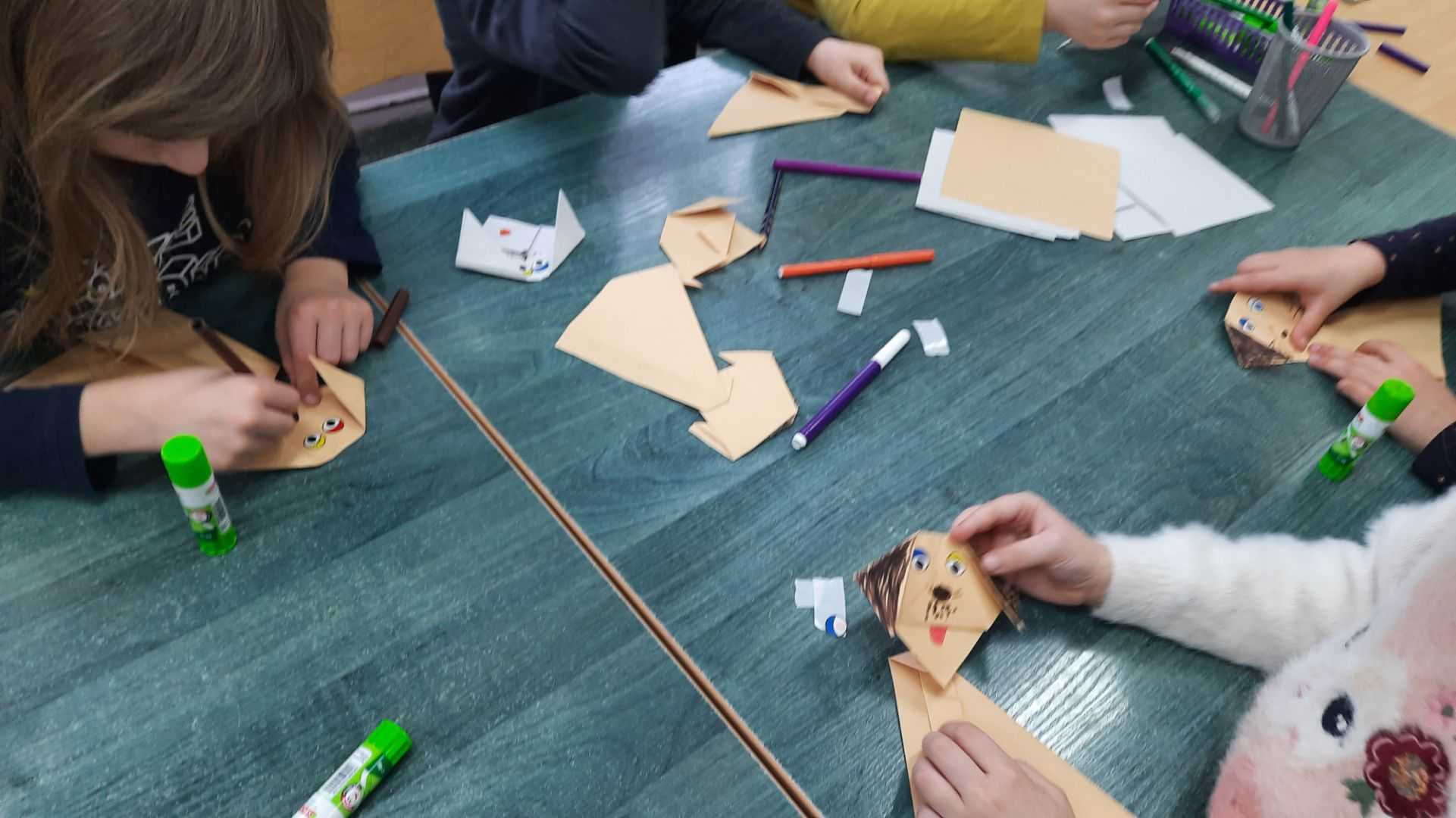 Przedszkolaki składają pieski z papieru techniką origami.