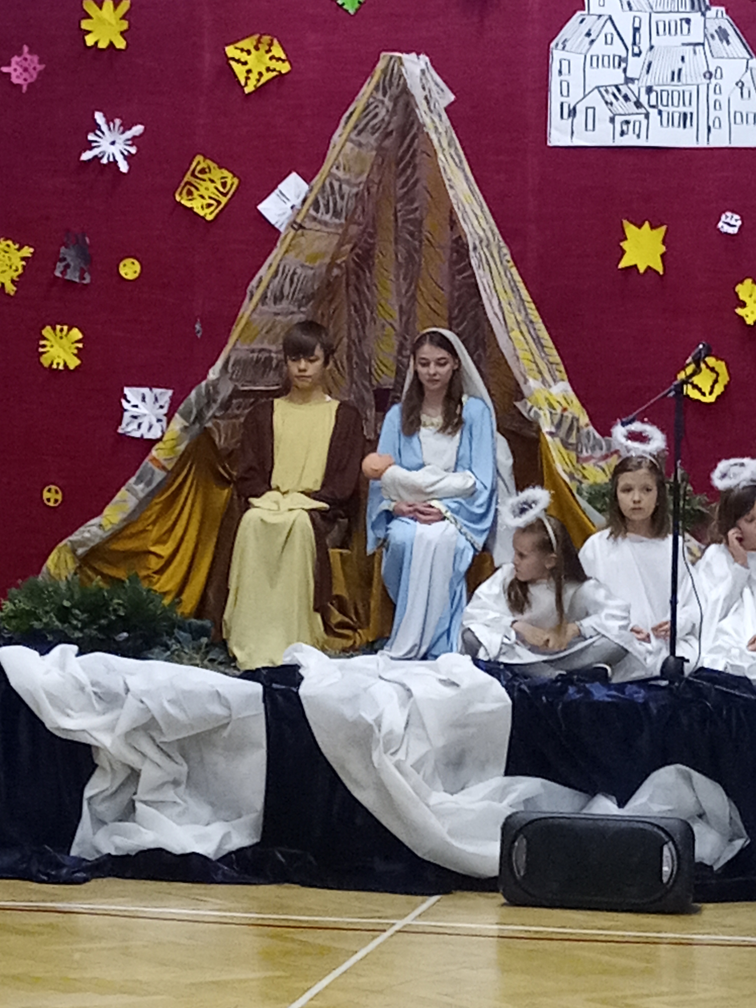 Na scenie stoi ustawiona grota. W jej wnętrzu siedzi Józef i Maryja z Dzieciątkiem.