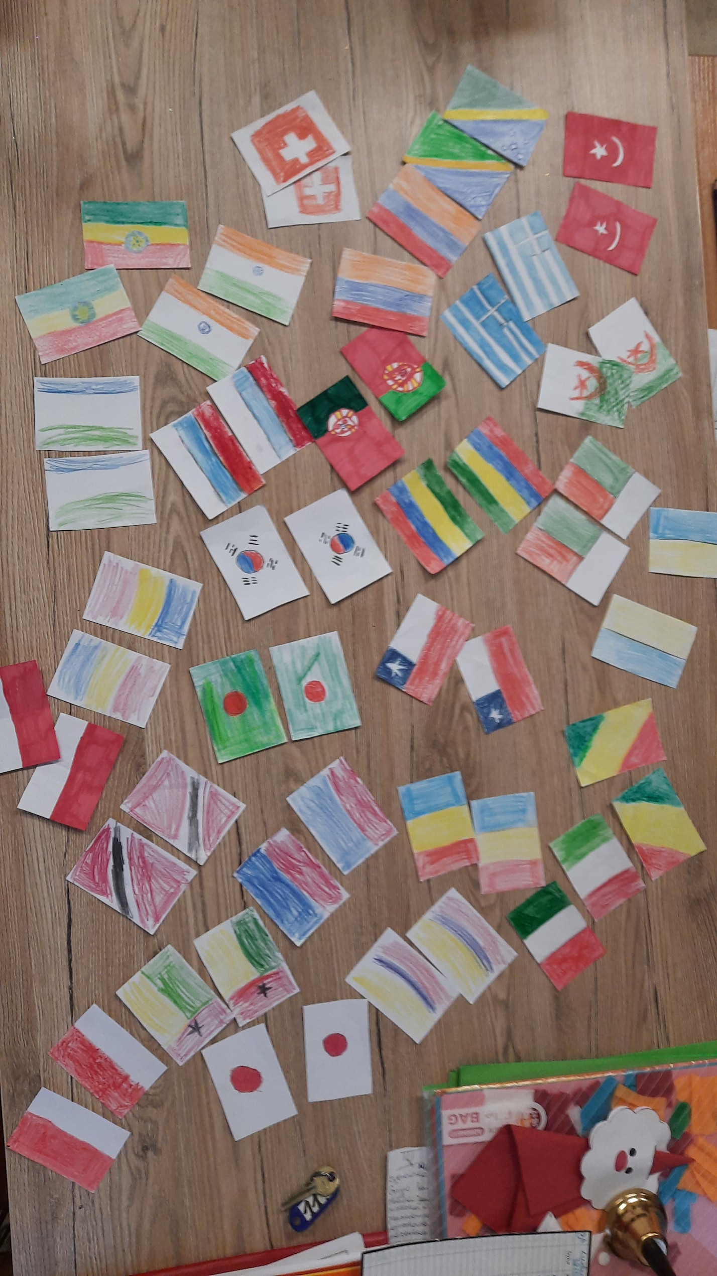 Na stole rozłożono rysunki flag różnych państw przygotowane przez dzieci.