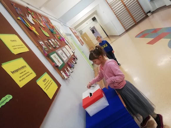 Dziewczynka wrzuca do urny kartę głosowania.