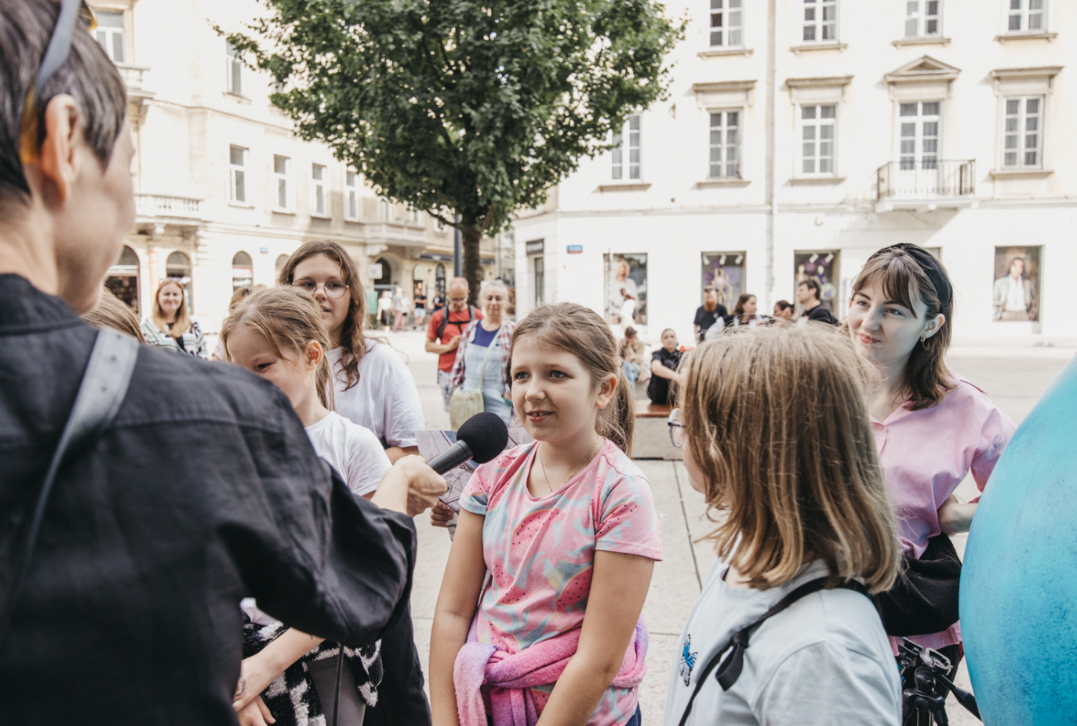 Na zdjęciu widać dziewczynkę udzielającą wywiadu oraz publiczność dookoła. fot. -p. Piotr Łabanow