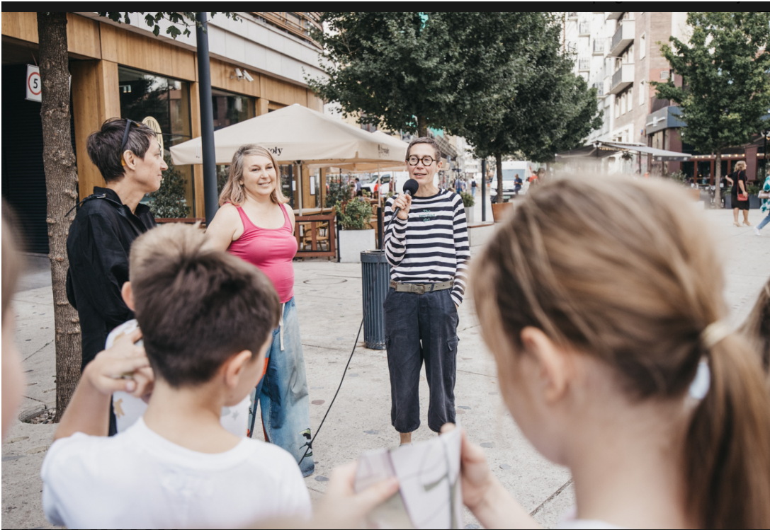 Zdjęcie przedstawia autorkę rzeźby "Pisklę. Drozd śpiewak" p. Joannę Rajkowskiej podczas przemowy oraz publiczność w dniu performance'u. fot. -p. Piotr Łabanow