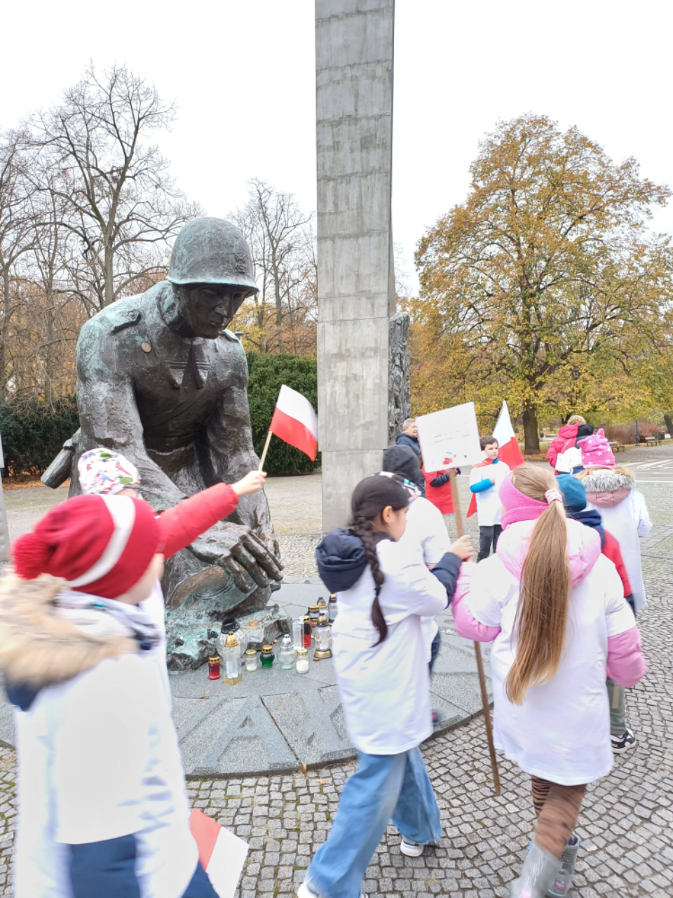 Dzieci z biało-czerwonymi flagami pod pomnikiem Sapera.