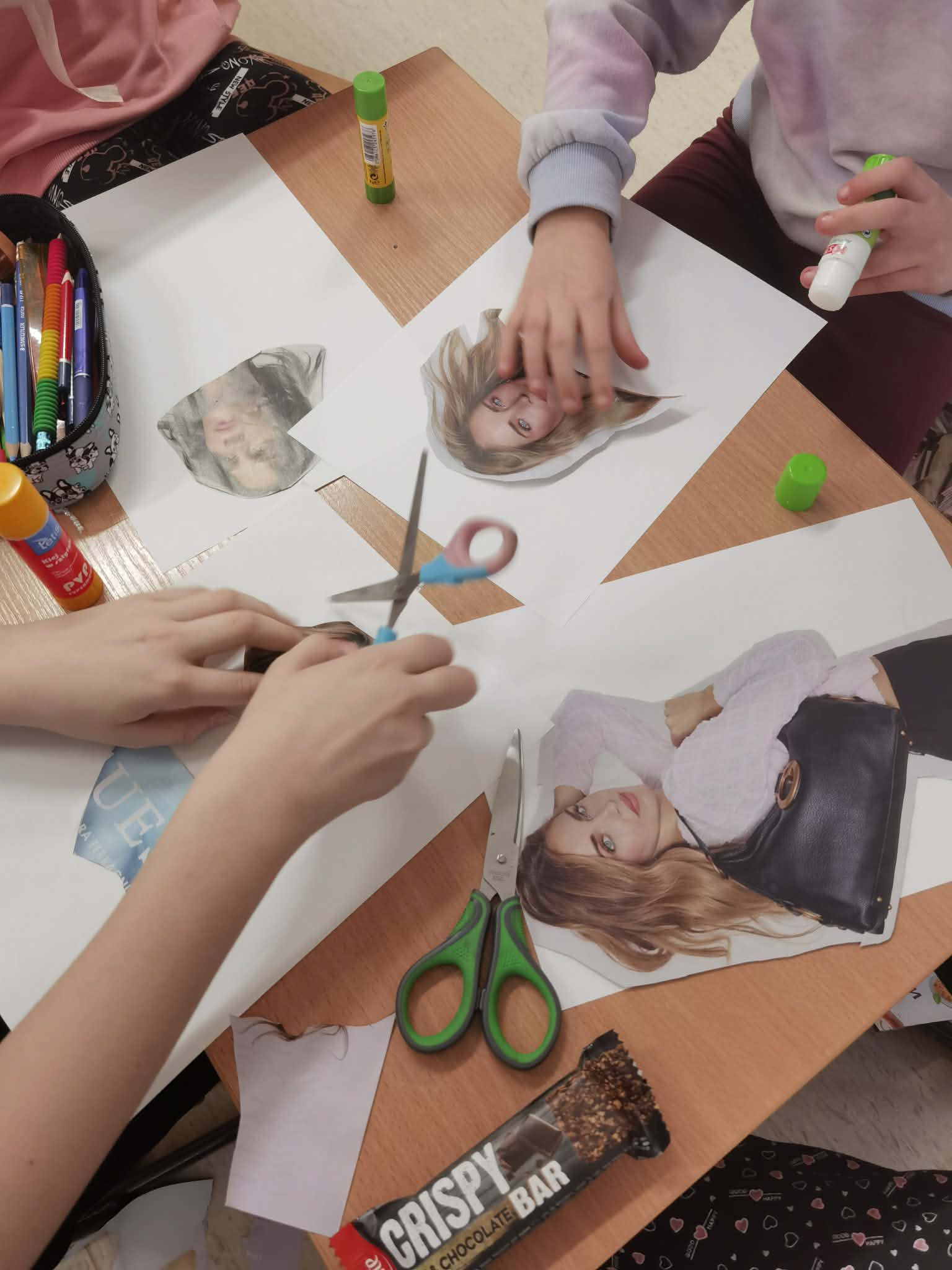 Na stoliku leżą wycinki z gazet projekt&oacute;w ubrań i nożyczki.