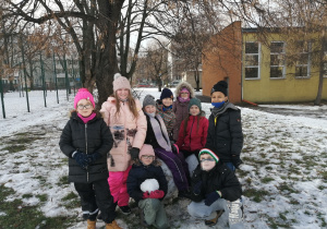 Uczniowie stoją i siedzą na kulach śnieżnych.