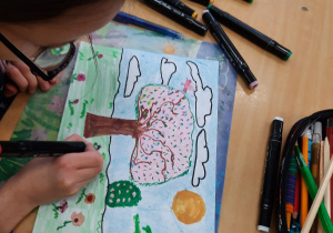 Dziewczynka pisakami wykonuje obraz wiosennego sadu.