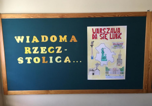 Dekoracja tablicy w świetlicy szkolnej z wykorzystaniem plakatu wykonanego przez klasę 2b reklamującego Warszawę.