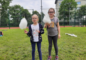 Dwie dziewczynki stoją na tle boiska w ręku trzymają watę cukrową.