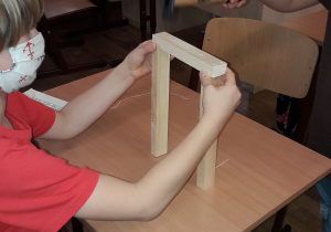 Uczeń przygotowuje drewniane deseczki do zbicia konstrukcji liczydła.