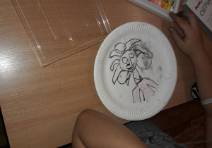 Uczeń rysuje na talerzu portret.
