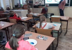 Uczniowie słuchają prezentacji o malarstwie Pabla Picassa i przygotowują się do malowania talerzy.