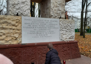 Uczestnik Biegu Niepodległości zapala znicz pod pomnikiem Żołnierzy AK Zgrupowania "Kryska".