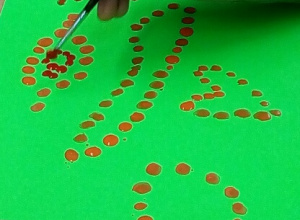 Na zielonej kartce uczeń maluje prace metodą kropkowania.