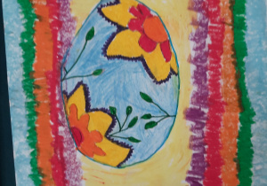Pisanka jest w kolorowej ramce (użyte kolory do ramki: zielony, pomarańczowy, czerwony i fioletowy). Niebieskie jajo jest ozdobione żółto-czerwonymi kwiatami i zielonymi liśćmi.