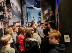Grupa uczniów zwiedza Muzeum Powstania Warszawskiego.