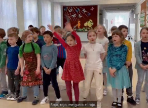 Dzieci ustawione w dwóch szeregach śpiewają piosenkę w języku hiszpańskim.