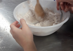 Dzieci mieszają produkty łyżką.