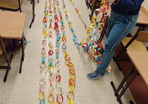 Uczniowie rozkładają łańcuchy na podłodze. Mierzą, który z nich jest najdłuższy.