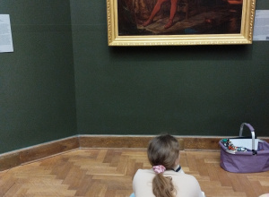 Ucznioowie w sali muzealnej siedzą na podłodze.