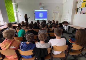 Uczniowie zgromadzili się przed tablicą multimedialną. Oglądają prezentację. fot. p. Moryc