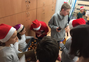 Uczniowie nachylają się nad skrzynką z muffinkami, aby odnaleźć swoje ulubione dodatki.