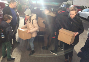 Po dotarciu do Domu Dziecka nr 2 im. Janusza Korczaka, wolontariusze wypakowują z samochodu przywiezione paczki.