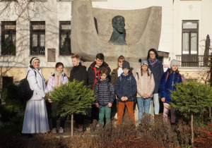 Grupa wolontariuszy wraz z opiekunami przy popiersiu Janusza Korczaka.