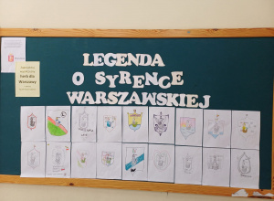 Na zdjęciu widzimy tablicę korkową z ekspozycją prac plastycznych wykonanych przez dzieci. Tablica ozdobiona jest dużym białym napisem z papieru: "LEGENDA O SYRENCE WARSZAWSKIEJ".