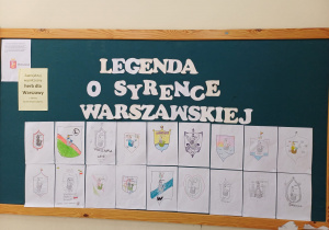 Na zdjęciu widzimy tablicę korkową z ekspozycją prac plastycznych wykonanych przez dzieci. Tablica ozdobiona jest dużym białym napisem z papieru: "LEGENDA O SYRENCE WARSZAWSKIEJ". Prace przedstawiają różne interpretacje herbu Warszawy, na którym głównym motywem jest syrenka — symbol miasta. Pod napisem znajdują się 18 kolorowych rysunków przypominających herby, z różnorodnymi wizerunkami syrenek.