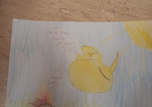 Na zdjęciu znajduje się ilustracja kurczaka, który stoi na jednej nodze na trawie i mówi „ nie mam czasu, spieszę się”.
