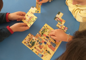 Dzieci układają puzzle obrazujące targ w Afryce.