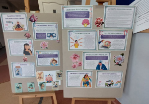 Na zdjęciu widać dwie tablice informacyjne ustawione na drewnianych sztalugach, przygotowane prawdopodobnie z okazji Światowego Dnia Zdrowia Psychicznego. Całość ma formę edukacyjnej gazetki szkolnej lub wystawy.