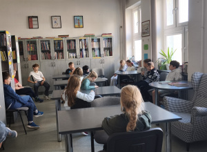 Na zdjęciu znajduje się grupa uczniów przebywających w szkolnej bibliotece.