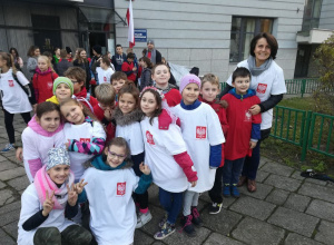 Uczniowie w białych i czerwonych koszulkach gotowi do biegu.